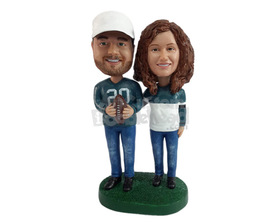 Sporty couple wearing their team's jerseys, holding a ball Personalized Bobblehead